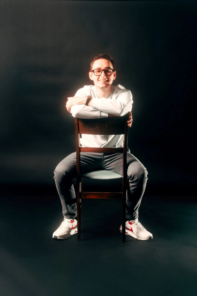 One of our developers seated on a chair against a black background